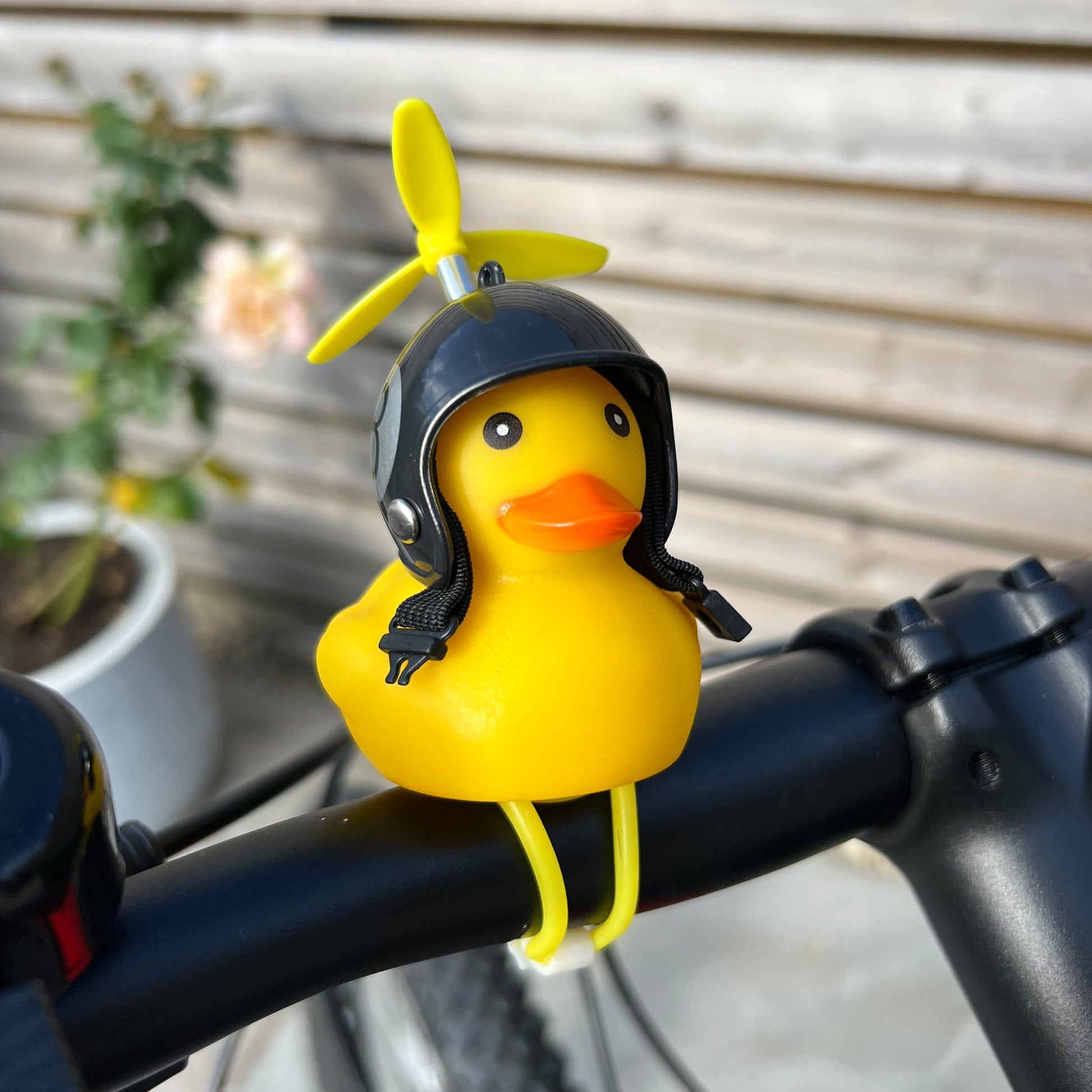 Yellow rubber duck with a helmet and propeller on a bicycle handlebar